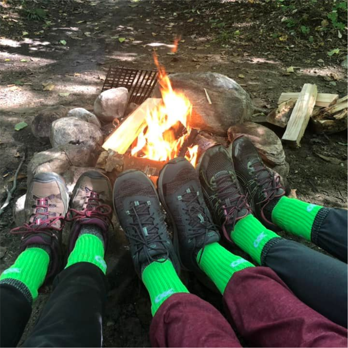 Pieds de participants à la randonnée de Randolyme devant un feu